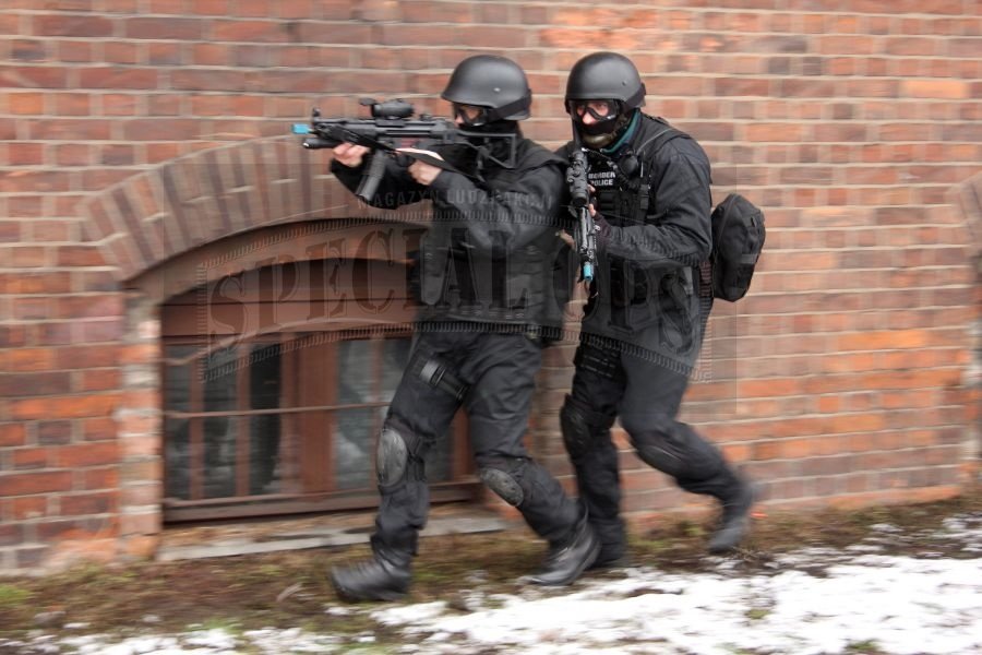 Operatorzy warszawskiego WZD I w typowym wyposażeniu do działań w terenie zabudowanym, podczas szybkiego podejścia do obiektu.
