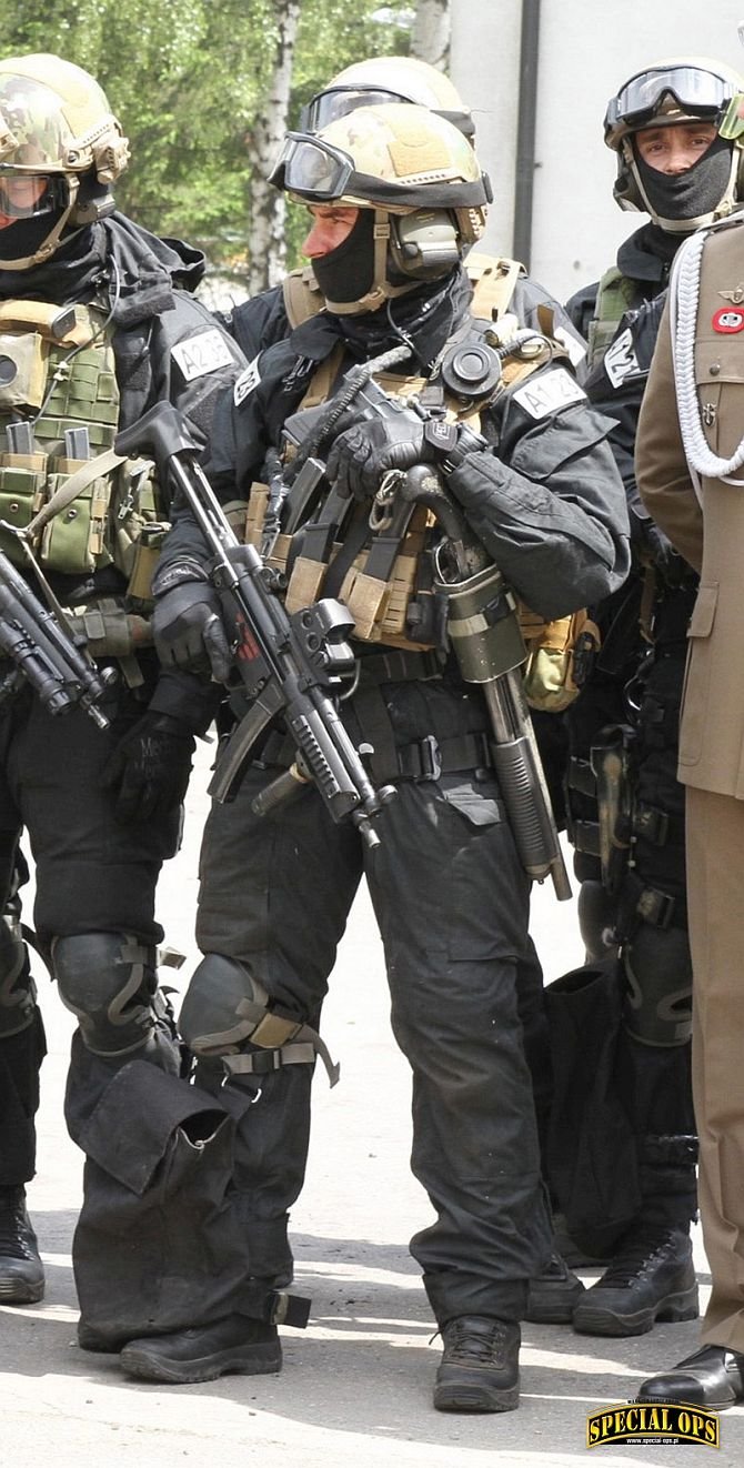 Fot. 10. Widok sylwetki operatora Zespołu Bojowego A, uzbrojonego w pm MP5A5 z łożem BT TL-99A1 3 rail, dodatkowym chwytem przednim VFG  i celownikiem holograficznym  EOTech XPS3. U boku strzelba  gładkolufowa Remington 870 SBS.