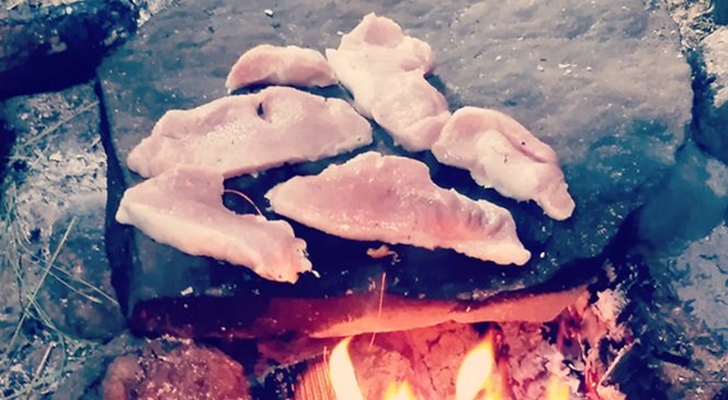 Smażenie mięsa nad ogniskiem w lesie