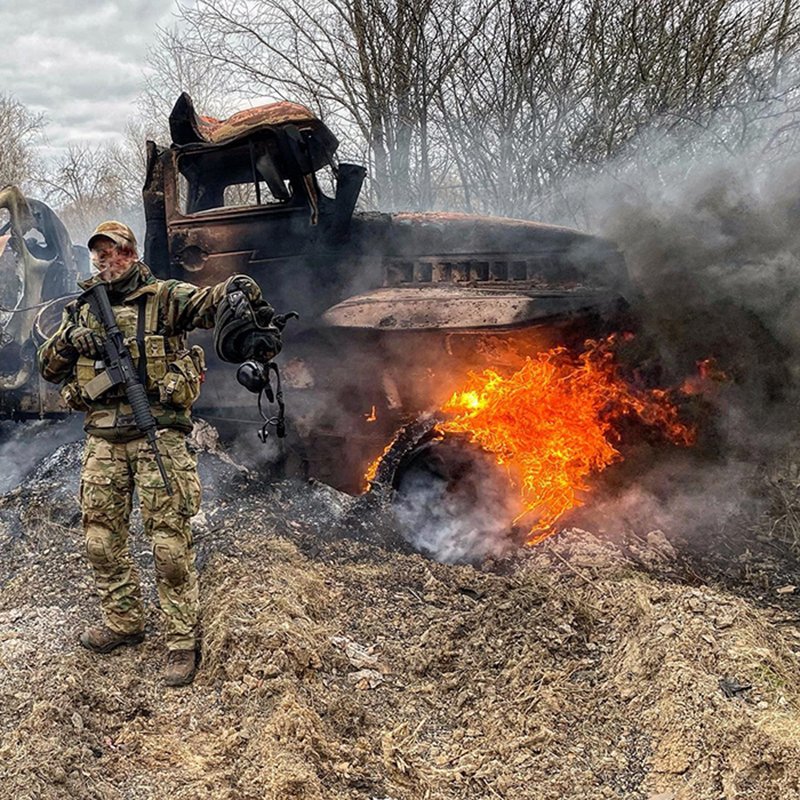 Ukraiński żołnierz przy płonącej rosyjskiej ciężar&oacute;wce. Foto. MON Ukrainy