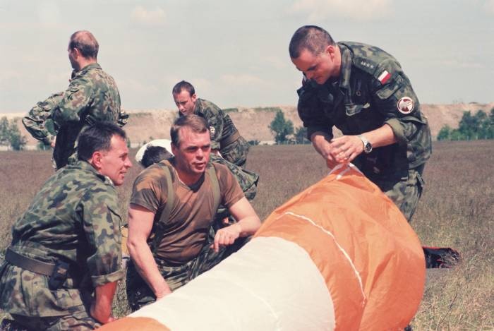 Układanie spadochron&oacute;w po skokach w 25DKPow. Pośrodku płk Jan Kempara a obok kpt. Piotr Patalong i kpt. Arkadiusz Kups - 1998 r.