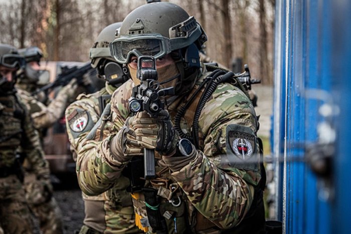 umundurowany funkcjonariusz mierzy z broni