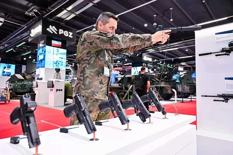 człowiek mierzy z pistoletu na stoisku targowym z bronią