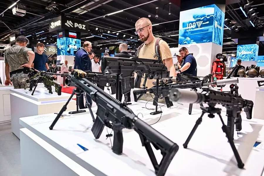 zwiedzajacy na targach ogladaja karabiny