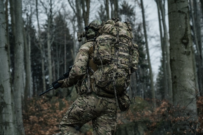 żołnierz w umundurowaniu i z plecakiem w lesie