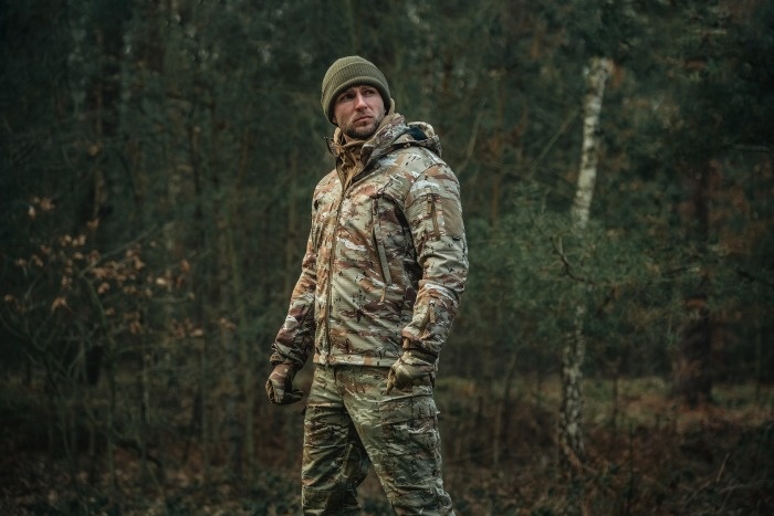 mężczyzna w kurtce multicam w lesie