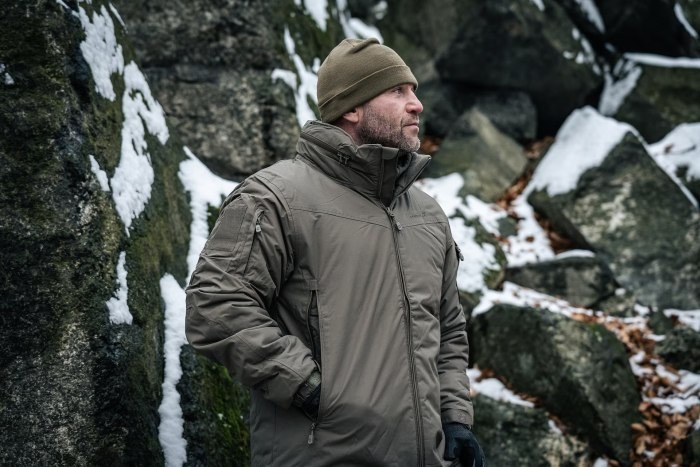 mężczyzna w szarej kurtce na tle skał