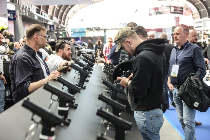 odwiedzający targi oglądają broń na stoisku