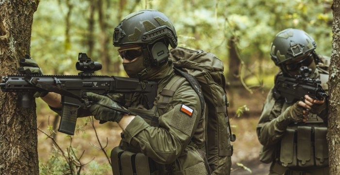 żołnierz w odzieży taktycznej z karabinem w lesie