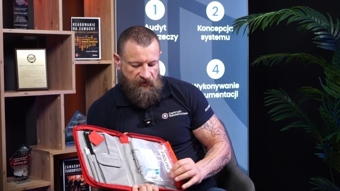 mężczyzna z brodą pokazuje zawartosć apteczki