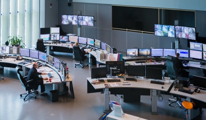 mnóstwo monitorów ustawionych na półokrągłych biurkach